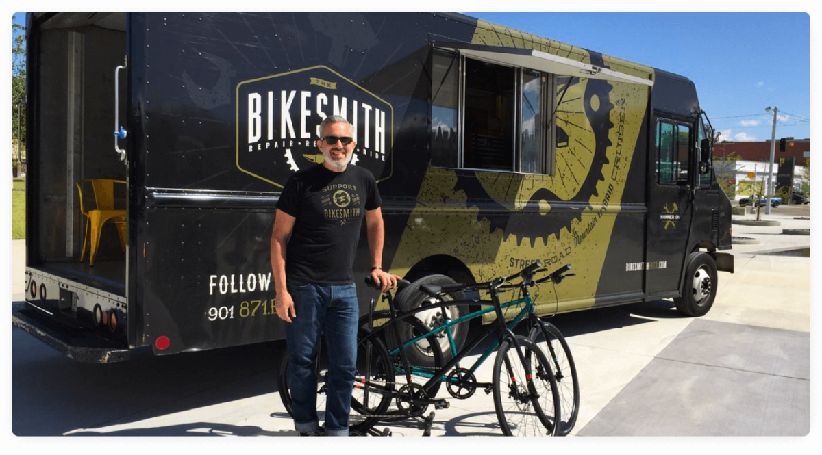 A picture of the founder of The Bikesmith, a mobile bike repair business, with his truck in the background.