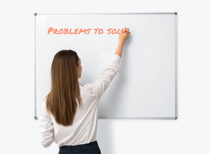A woman writing "Problems to sol.." on a whiteboard